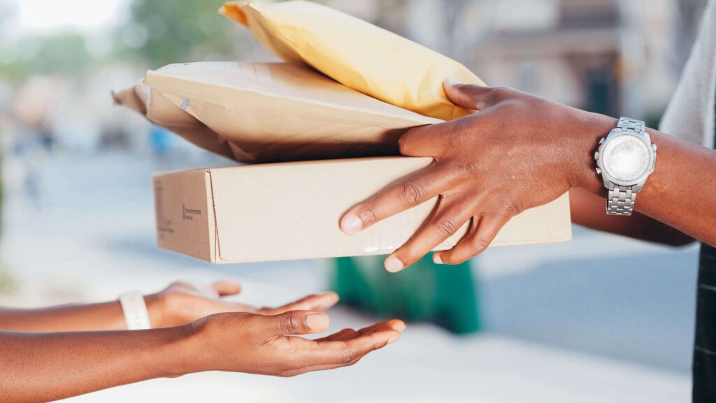 Imagem mãos masculina entregando pacotes de encomenda para mãos femininas